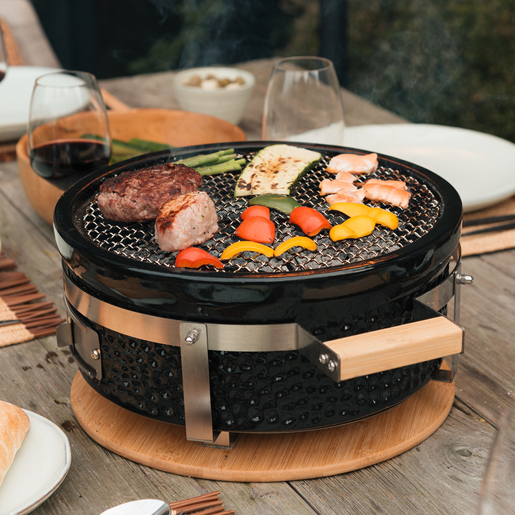 OUTR Braza Table Grill Round in gebruik buiten.