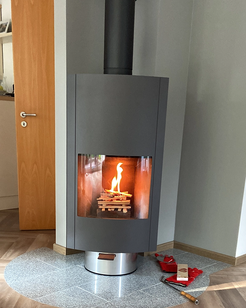 Leenders Hymme houtkachel met vuur in een lichte woonkamer